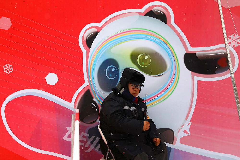 Как выглядит Пекин перед Олимпиадой. Фото: gazeta.ru. Сотрудник охраны на фоне плаката с символикой Олимпийских игр в Пекине